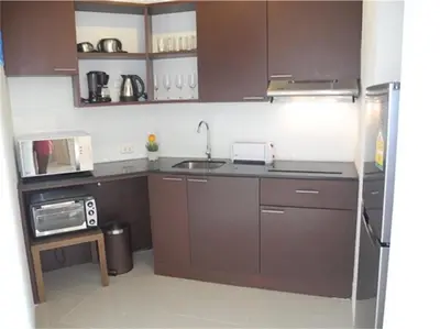 a small kitchen with brown cabinets and a sink at Chic Karon Nice Apartment close to Karon Beach in Karon Beach