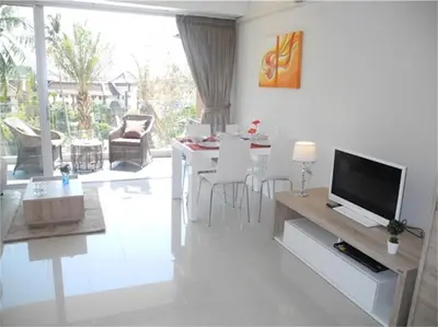 a living room with a television and a table with chairs at Chic Karon Nice Apartment close to Karon Beach in Karon Beach