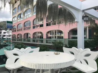 a white table and chairs in front of a pink building at Baan Petcharat in Patong Beach