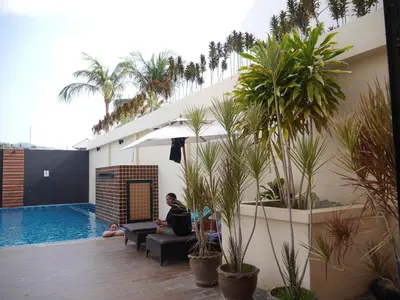 a man sitting on a couch next to a swimming pool at Baan Petcharat in Patong Beach