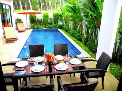 a table and chairs in front of a swimming pool at Intira Villa Rawai 2 bedrooms Villa in Rawai Beach
