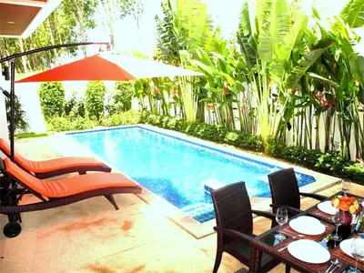 a swimming pool with two chairs and an umbrella at Intira Villa Rawai 2 bedrooms Villa in Rawai Beach