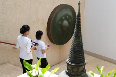 two women standing next to a wall with a sculpture at Andara Resort Villas in Kamala Beach