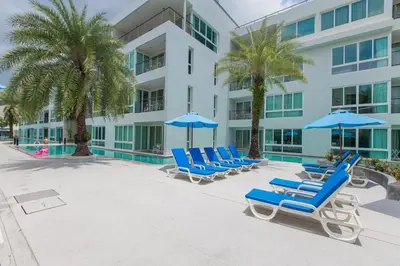 a group of blue lounge chairs and umbrellas next to a building at The Palms, Kamala Beach - SHA Extra Plus in Kamala Beach
