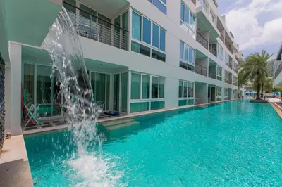 a swimming pool with a fountain in front of a building at The Palms, Kamala Beach - SHA Extra Plus in Kamala Beach
