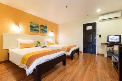 a hotel room with two beds and a flat screen tv at Vacation Village Phra Nang Inn - SHA Extra Plus in Ao Nang Beach