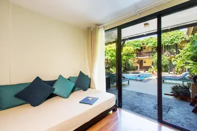 a living room with a couch and a large window at Vacation Village Phra Nang Inn - SHA Extra Plus in Ao Nang Beach