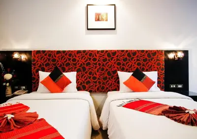 two beds in a room with a red wall at The Yorkshire Hotel - SHA Certified in Patong Beach