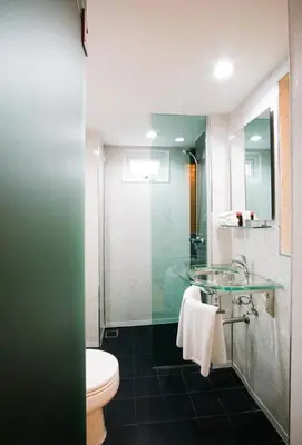 a bathroom with a toilet and a glass shower at The Yorkshire Hotel - SHA Certified in Patong Beach