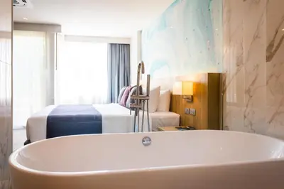 a bathroom with a tub and a bedroom with a bed at Coconut Village Resort Phuket - SHA Extra Plus in Patong Beach