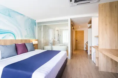 a bedroom with a large bed and a bathroom at Coconut Village Resort Phuket - SHA Extra Plus in Patong Beach