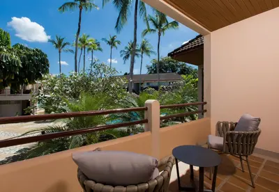 a balcony with chairs and tables and palm trees at Coconut Village Resort Phuket - SHA Extra Plus in Patong Beach