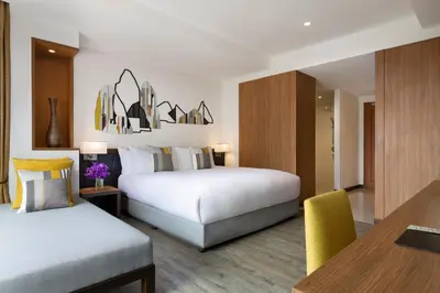 a hotel room with two beds and a table at Avani Ao Nang Cliff Krabi Resort in Ao Nang Beach