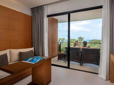 two people sitting on a balcony in a hotel room at Novotel Phuket Kata Avista Resort and Spa in Kata Beach