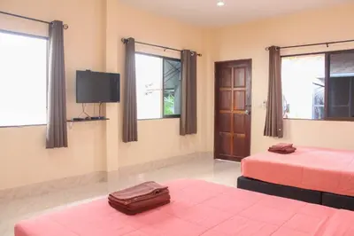 a room with two beds and a flat screen tv at Sirikul Mansion in Nai Yang Beach