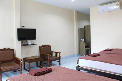 a bedroom with two beds and a flat screen tv at Sirikul Mansion in Nai Yang Beach
