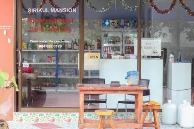 a shop with a table and two stools in front of a window at Sirikul Mansion in Nai Yang Beach