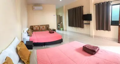 a room with two beds and a television in it at Sirikul Mansion in Nai Yang Beach