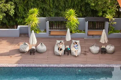 two women are sitting in pillows next to a pool at Phuvaree Resort in Patong Beach