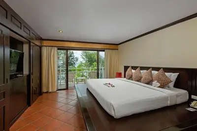 a bedroom with a large white bed and a balcony at The Front Village - SHA Plus in Karon Beach