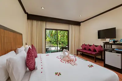 a hotel room with a bed with flowers on it at The Front Village - SHA Plus in Karon Beach