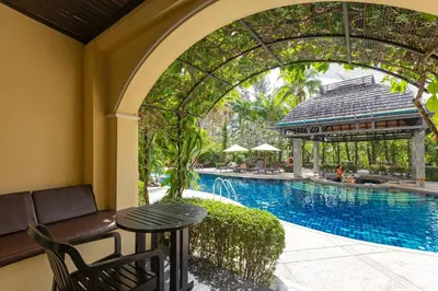 a patio with a table and a swimming pool at The Front Village - SHA Plus in Karon Beach