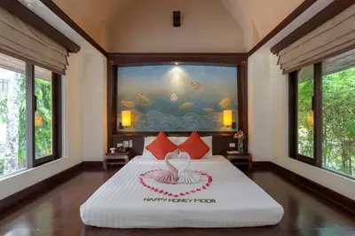 a bedroom with a large bed with a large window at The Village Resort - SHA Plus in Karon Beach