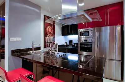 a kitchen with red cabinets and a black counter top at Absolute Bangla Suites in Patong Beach