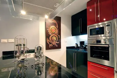 a kitchen with black counter tops and red cabinets at Absolute Bangla Suites in Patong Beach