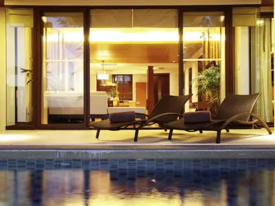 a pool with two lounge chairs next to a house at Mövenpick Resort Bangtao Beach Phuket in Bang Tao Beach