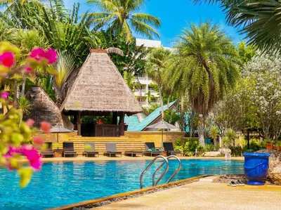 a resort pool with a gazebo and palm trees at Paradox Resort Phuket in Karon Beach