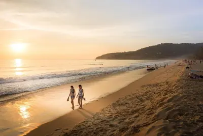 two people walking on the beach at sunset at Paradox Resort Phuket in Karon Beach