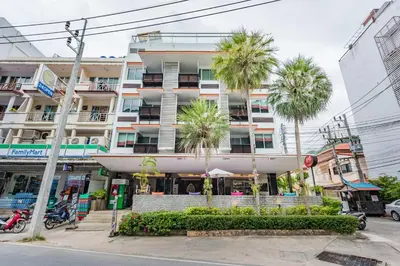 a building with palm trees in front of it at Kata Beach Studio Phuket in Kata Beach