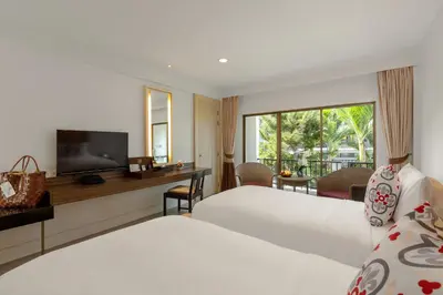 a hotel room with two beds and a television at Sawaddi Patong Resort & Spa by Tolani in Patong Beach