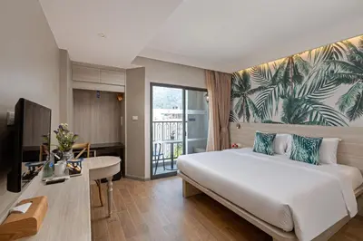 a hotel room with a large bed and a desk at Sawaddi Patong Resort & Spa by Tolani in Patong Beach