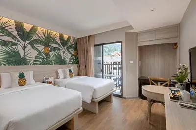 a hotel room with two beds and a balcony at Sawaddi Patong Resort & Spa by Tolani in Patong Beach