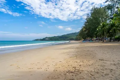 a sandy beach with palm trees and the ocean at Sunwing Kamala Beach in Kamala Beach
