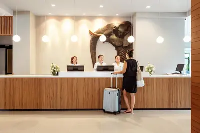 a woman standing at a reception desk with an elephant on the wall at Sunwing Kamala Beach in Kamala Beach