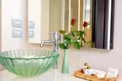 a bathroom sink with a green bowl and a vase at Baan Karonburi Resort in Karon Beach