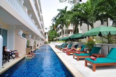 a hotel swimming pool with people sitting on lounge chairs at Baan Karonburi Resort in Karon Beach