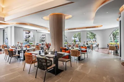 a restaurant with tables and chairs and windows at Amora Beach Resort Phuket in Bang Tao Beach