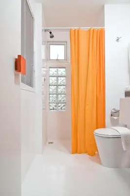 an orange shower curtain in a bathroom with a toilet at The Album Hotel in Patong Beach
