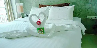 a white bed with white towels and a box with hearts at The Album Hotel in Patong Beach