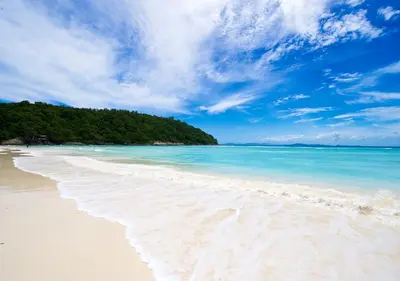 a beach with white sand and blue water and trees at Racha Island Resort (Rayaburi) in Ko Racha Yai