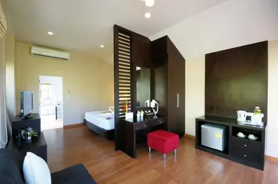 a living room with a bed and a red chair at Palm Paradise, Aonang Resort in Ao Nang Beach