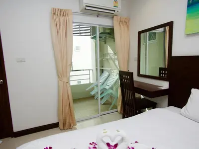 a bedroom with a bed and a desk and a balcony at Q Victory Patong Hotel in Patong Beach