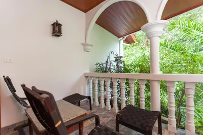 a porch with chairs and a table and a window at Tropica Bungalow Beach Hotel in Patong Beach