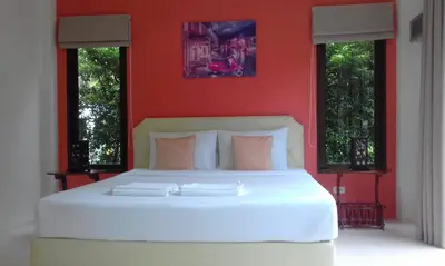 a bedroom with a white bed with a red wall at Phuket Sirinapha Resort in Nai Yang Beach
