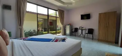 a bedroom with a bed and a table with chairs at Phuket Sirinapha Resort in Nai Yang Beach