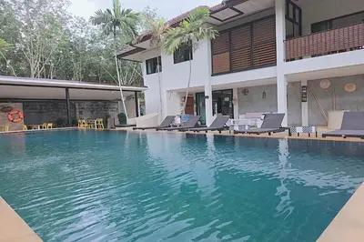 a swimming pool in front of a building with chairs at Nongthale Mountain View in Klong Muang Beach